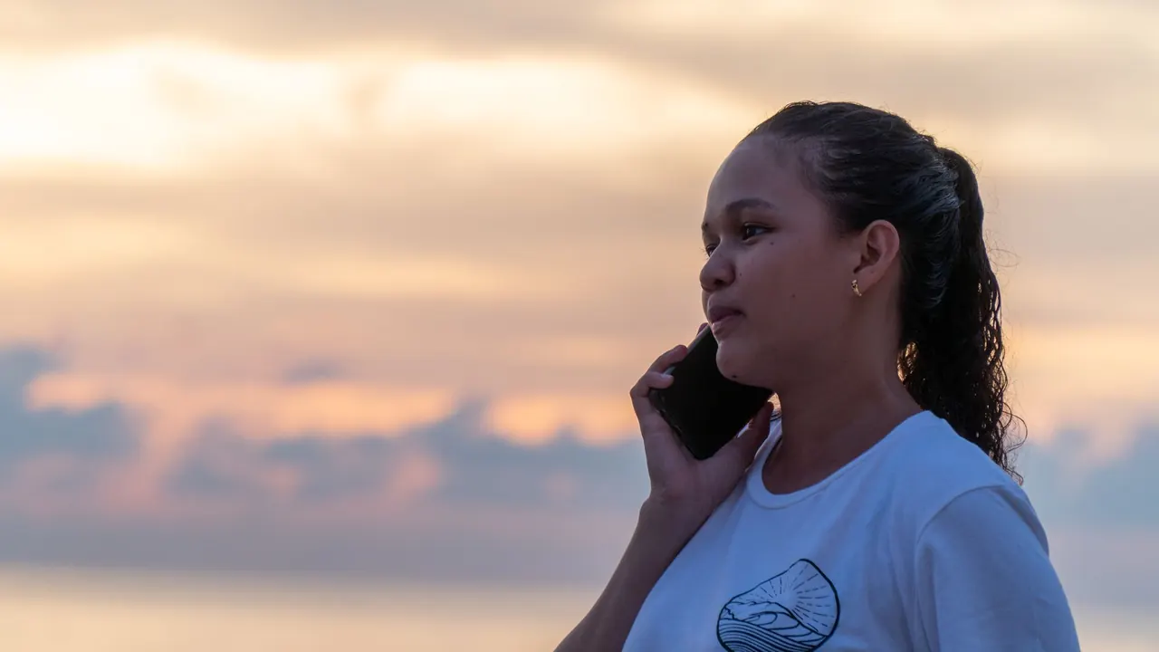 Woman on the beach with her phone at sunset