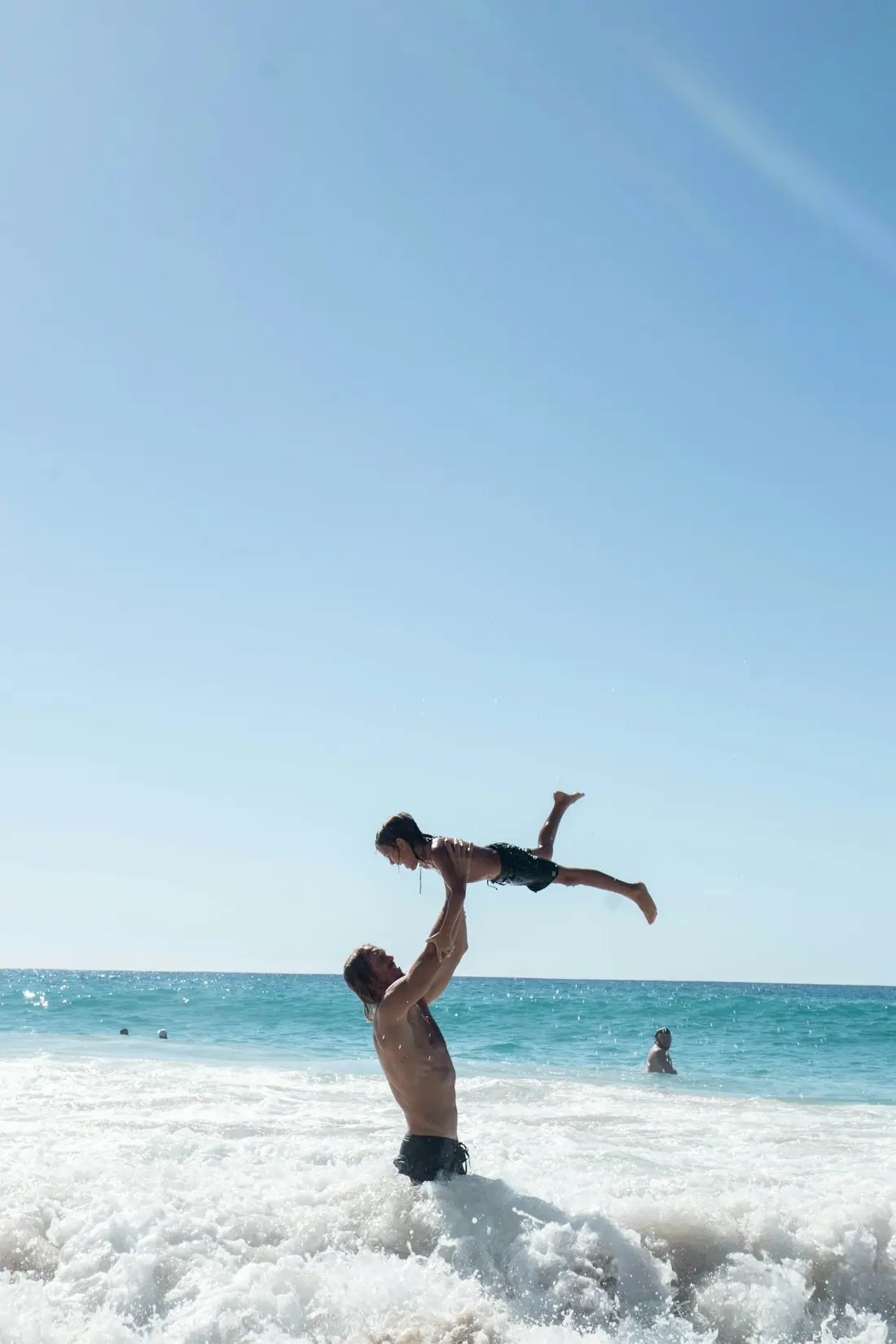 A father throwing his child up in the sea